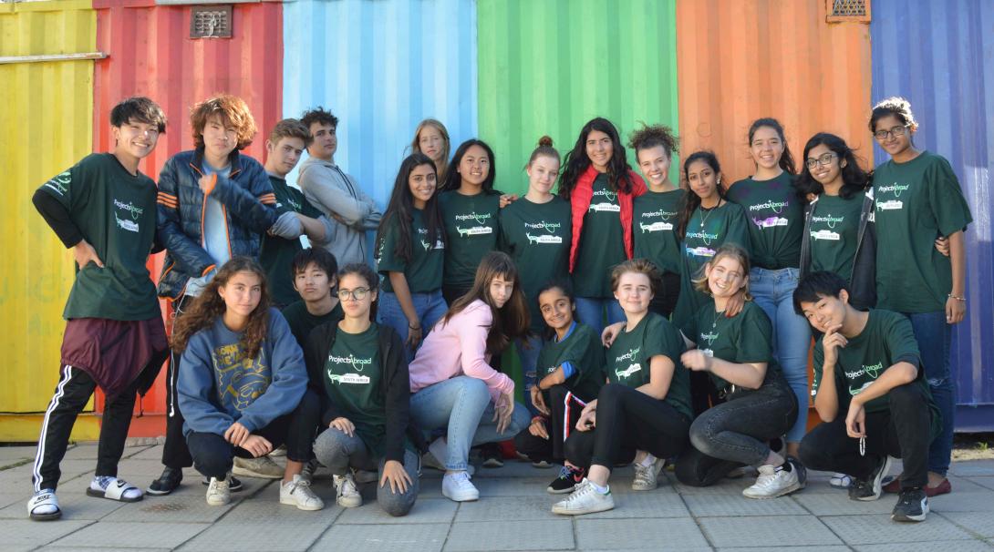 Freiwillige Schüler*innen im Projekt in Südafrika vor einem bunten Container in einem Township Schüler*innen im Freiwilligeneinsatz in Südafrika posieren für ein Foto